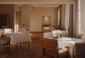 Un comedor con mesas y sillas blancas. en Forestis Dolomites, en Bresanona