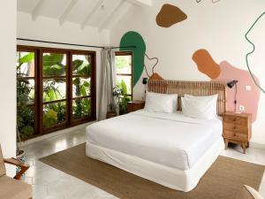 een slaapkamer met een wit bed en ramen bij Happy Together By Kresna Hospitality in Seminyak +196 foto's