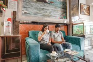 a man and woman sitting on a couch drinking coffee at FabHotel New Shanti in Allahābād