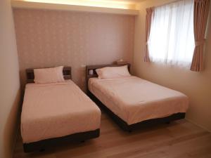 due letti in una piccola stanza con una finestra di 富津 Fun Base a Futtsu Altre 37 foto