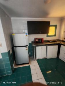 a kitchen with a white refrigerator and green tiles at Elixir Two Bed Rooms in Hurghada