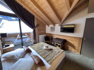 a room with two beds and a tv in a room at Hôtel Les Airelles in La Clusaz