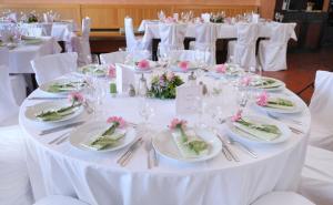 een witte tafel met borden, glazen en bloemen erop bij Hotel Grasbrunner Hof in Grasbrunn