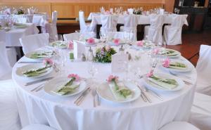 una mesa blanca con platos, vasos y flores. en Hotel Grasbrunner Hof, en Grasbrunn