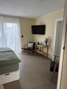 Un dormitorio con una cama, un televisor y una silla. en Fewo Hommage, en Spremberg