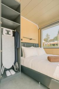 Cozy Nomad Cabin 1 Min Walk to Bang Tao Beach في Ban Lum Fuang: غرفة نوم صغيرة بها سرير ونافذة