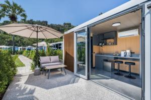 Cozy Nomad Cabin 1 Min Walk to Bang Tao Beach في Ban Lum Fuang: مطبخ مفتوح ومنطقة معيشة لبيت صغير