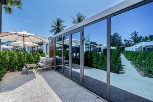 Cozy Nomad Cabin 1 Min Walk to Bang Tao Beach في Ban Lum Fuang: بيت زجاجي وبه كرسي ومظلة