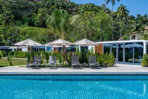 Cozy Nomad Cabin 1 Min Walk to Bang Tao Beach في Ban Lum Fuang: مسبح وكراسي ومظلات بجانب منتجع