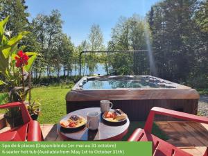 a hot tub with two plates of food on a table at Cozy Chalet by the Lake - Your Perfect Escape in Hébertville