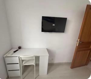 a white desk with a chair and a tv on a wall at Chez Soiz in Guipavas