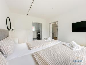 Cette chambre blanche dispose de 2 lits et d'une télévision. dans l'établissement Ferienhaus am Ringwall 19, à Duhnen