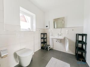 une salle de bains blanche avec toilettes et lavabo dans l'établissement Ferienhaus am Ringwall 19, à Duhnen 18 autres photos