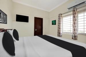 a bedroom with a white bed and a television at Super Hotel O Ramaraopet Near Kakinada Beach in Kākināda