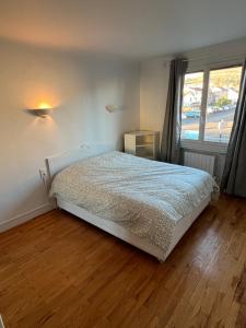 a bedroom with a bed and a large window at Le Toit des Volcans - 8 couchages - Terrasse privée et Wifi in Clermont-Ferrand
