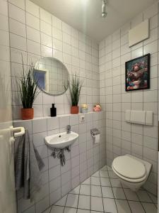 ビューラータールにあるFamilienapartment Buehlertal bei Buehl Baden Baden und Schwarzwaldの白いタイル張りのバスルーム(トイレ、シンク付)