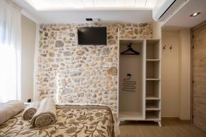 a bedroom with a stone wall with a bed and a tv at Portal Fosc Suites in Peniscola +30 photos