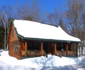 a log cabin with snow on the roof at Camp Quityerbellyachin in Greenville