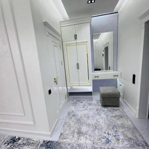 een badkamer met witte muren, een spiegel en een kruk bij Rent room 999 in Samarkand