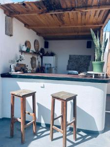 a kitchen with two wooden stools in front of a counter at Surf Sun Sea Lodge in Wassane