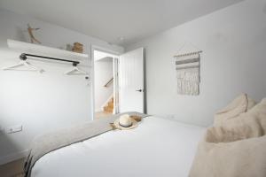 a white bedroom with a bed with a hat on it at 10 Cannery Row - Stunning Views - Pet Welcome - Free WiFi & Parking in Hayle