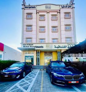 two luxury cars parked in front of a building at Arkan Al Barzah Hotel Apartment in Sur