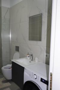 ein Badezimmer mit Waschbecken, Toilette und Spiegel in der Unterkunft DREAM Apartment in Kamëz + 17 Fotos