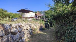 a stone wall next to a building with an umbrella at La Yourte Des Abeilles in Les Preyrauds +16 photos