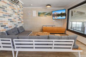 Una sala de estar con un sofá y un televisor. en לה וילה - וילה משפחתית עם בריכה פרטית מחוממת ומקורה, en Bet Dagan