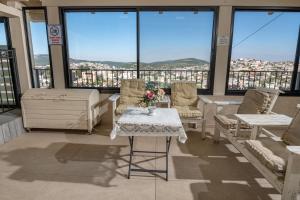 Una sala de estar con mesa y sillas y ventanas. en לה וילה - וילה משפחתית עם בריכה פרטית מחוממת ומקורה, en Bet Dagan