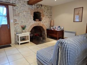 a living room with a brick fireplace and a desk at "Chambre Rose", L'Ancienne Poterie in Nancray-sur-Rimarde