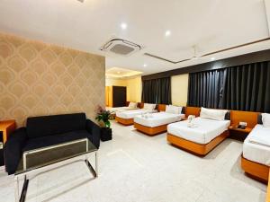 a hotel room with two beds and a couch at Dasara Executive in Tuljapur