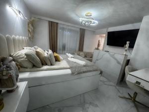 a white bedroom with a bed and a tv at Gold in Święta Katarzyna