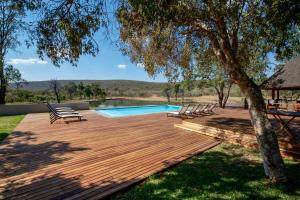 a wooden deck with chairs and a swimming pool at Ilanga Lodge Welgevonden Game Reserve in Welgevonden Game Reserve