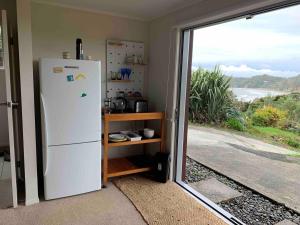 a kitchen with a refrigerator and a view of the ocean at Ocean view haven in Matapouri
