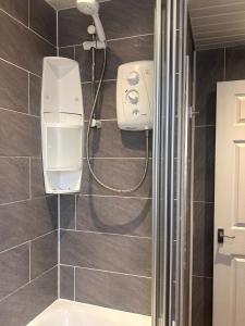 een douche in een badkamer met een wastafel en een douche bij Churchill Apartment- 4 Beds- Free Parking- Near NEC BHX & HS2 in Coleshill