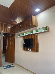 a room with wooden cabinets and a tv on a wall at Nestdormitory in Cochin