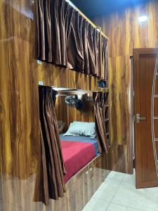 a room with a bed in a wooden wall at Nestdormitory in Cochin +5 photos