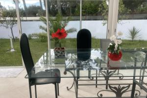 Spacious house in Tarnos near the beach في تارنوس: طاولة زجاجية عليها كرسيان وزهرة حمراء