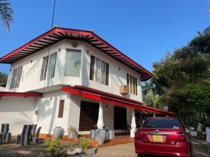 a red car parked in front of a house at Ayurveda Villa Rob Roy in Beruwala