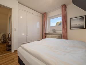 una camera da letto con un grande letto bianco e una finestra di Dacklünen a Wenningstedt