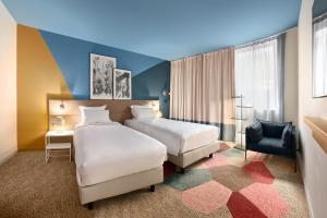 a hotel room with two beds and a desk at Radisson Hôtel Bordeaux Saint-Jean in Bordeaux