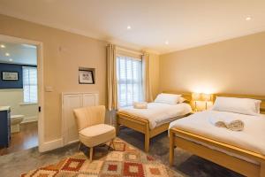 a bedroom with two beds and a chair and a television at Middle Cottage by Keepers Cottages in Sandwich
