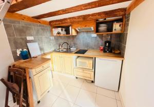 a small kitchen with white cabinets and a sink at Studio Piscine en Drôme Provençale Repas Asiatique sur demande in Taulignan