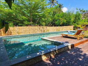 una piscina con un banco y una silla al lado en Villa Pesisi - 3 bdrs - beach walking distance, en Selong Belanak