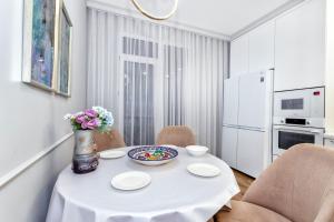 Большая двухкомнатная Люкс возле вокзал НУРЛЫЖОЛ في أستانا: مطبخ أبيض مع طاولة مع إناء من الزهور