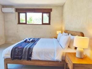 Un dormitorio con una cama y una ventana y una mesa. en Villa Pesisi - 3 bdrs - beach walking distance, en Selong Belanak