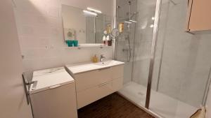 a white bathroom with a sink and a shower at Charmant T2 à 100m de la plage in Bénodet