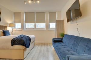 a bedroom with a blue couch and a tv at Aylward Queen Street, Studio Apartment Near City Centre, Gunwharf Quays in Portsmouth