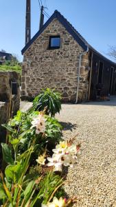 a stone church with flowers in front of it at Location en bordure du Trieux in Plourivo